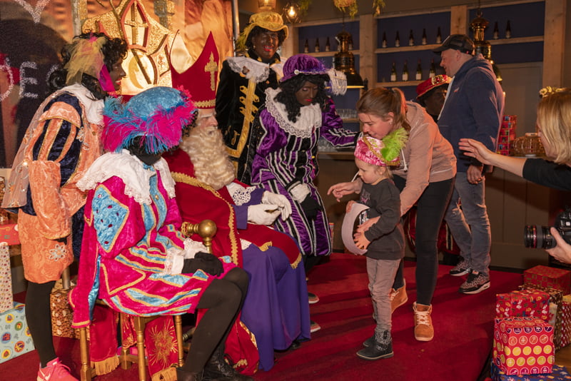 Vele kinderen met tekeningen langs Sinterklaas